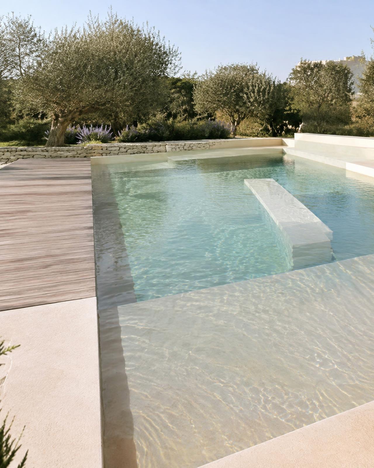 Piscina com prainha e deck em madeira em jardim mediterrâneo